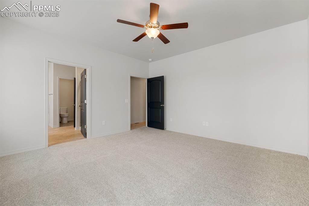 Image 18 of 22: Unfurnished bedroom with light carpet, ceiling fan, and connected bathroom