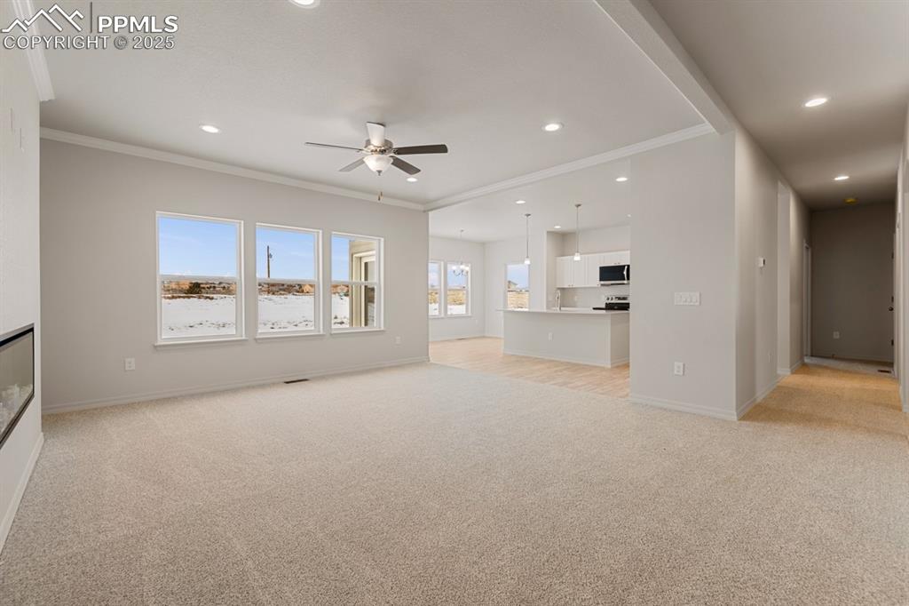 Image 9 of 22: Unfurnished living room featuring light colored carpet, crown molding, ceil