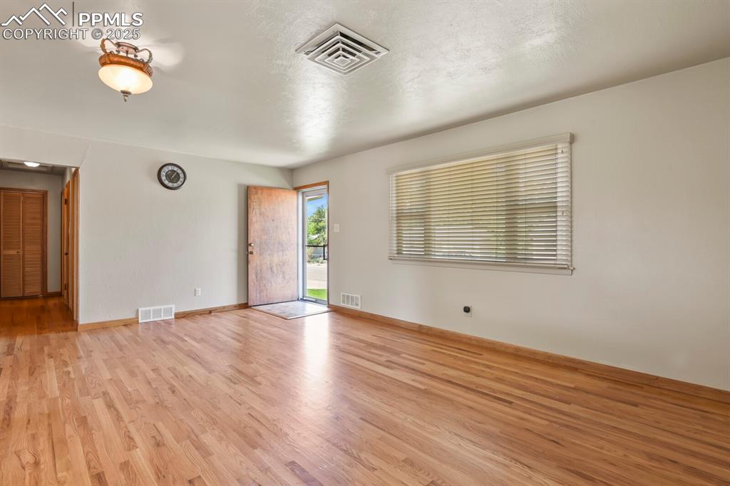 Image 6 of 24: Family room with light wood finished floors, wood blinds, looking at front 
