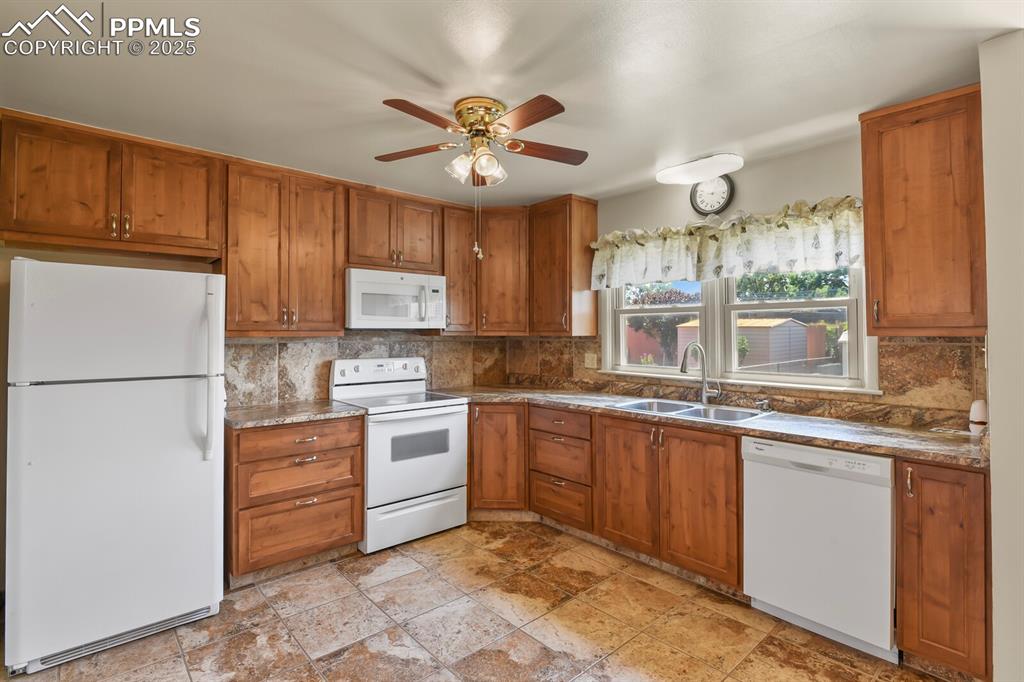Image 7 of 24: Kitchen featuring white appliances, solid wood cabinetry, backsplash, ceili