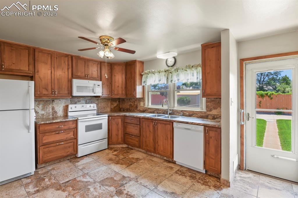 Image 8 of 24: Kitchen featuring white appliances, solid wood cabinetry, backsplash, and c