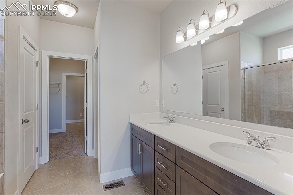 Image 9 of 10: Full bath featuring double vanity, light tile patterned floors, a shower st