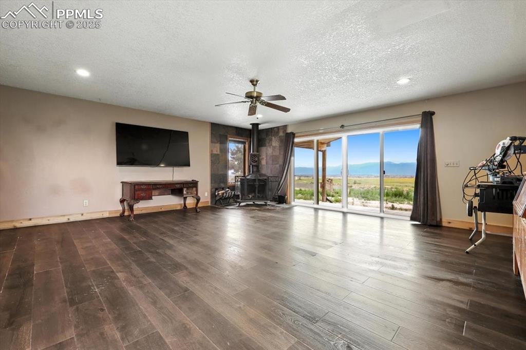 Image 12 of 29: Unfurnished living room featuring a wood stove, a textured ceiling, a ceili