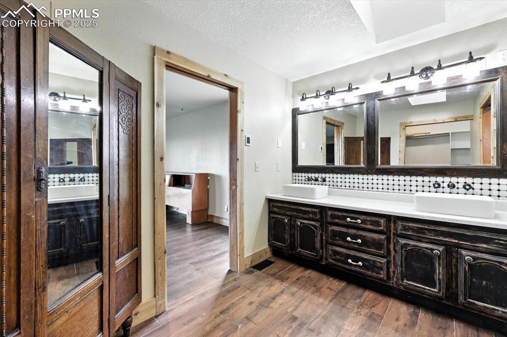 Image 15 of 29: Bathroom featuring double vanity, tasteful backsplash, wood finished floors