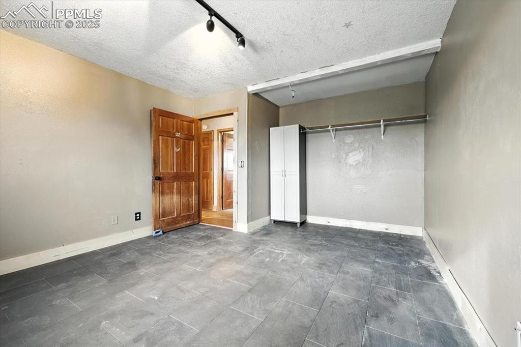 Image 18 of 29: Unfurnished bedroom featuring a textured ceiling, track lighting, and a clo