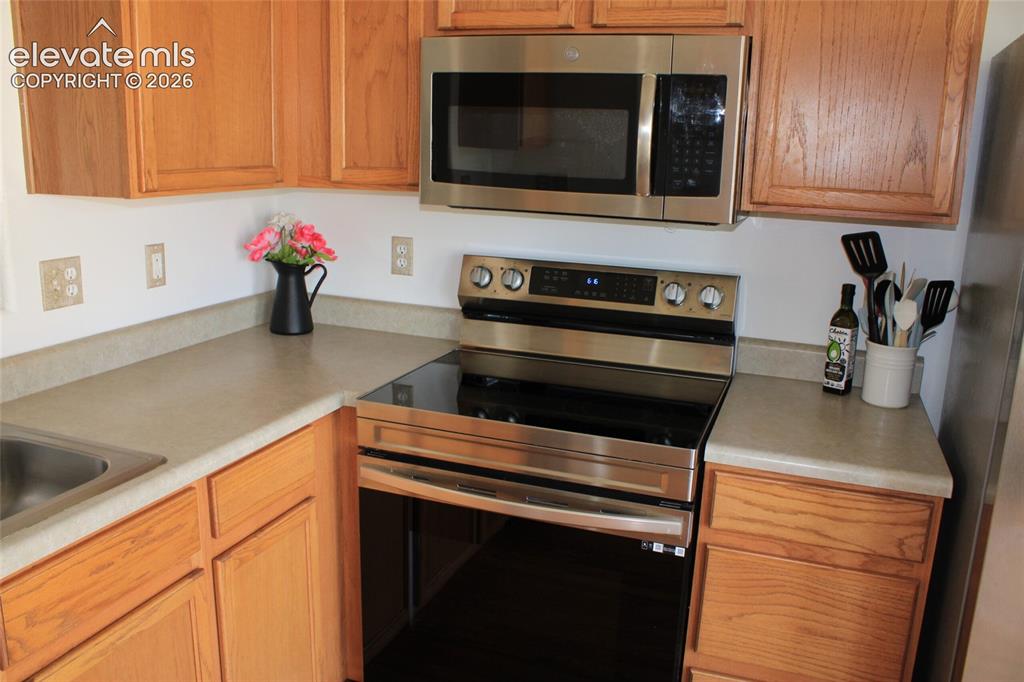 Image 15 of 31: Kitchen featuring natural wood cabinetry, light-toned countertops, stainles