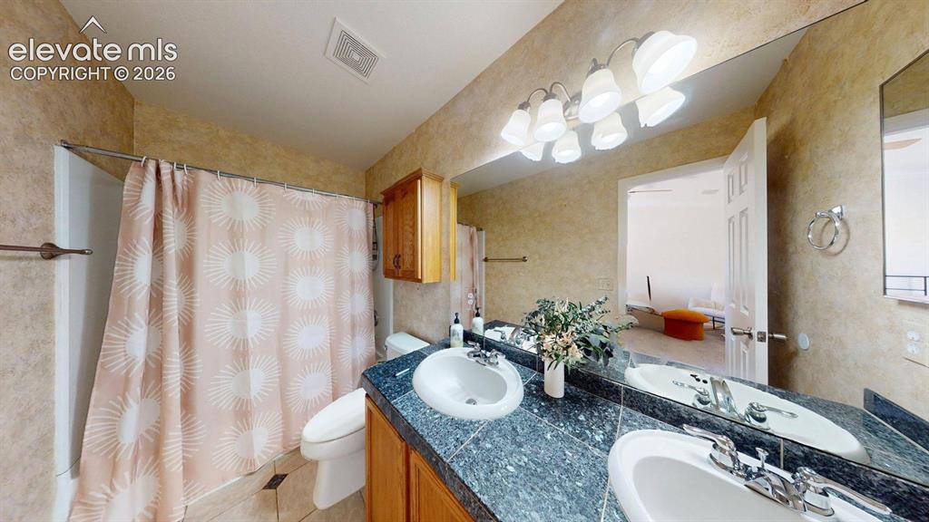Image 22 of 31: Dual vanity with integrated sinks and a dark speckled countertop, featuring