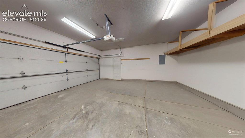 Image 27 of 31: Spacious two-car garage featuring a concrete floor, overhead lighting, an o