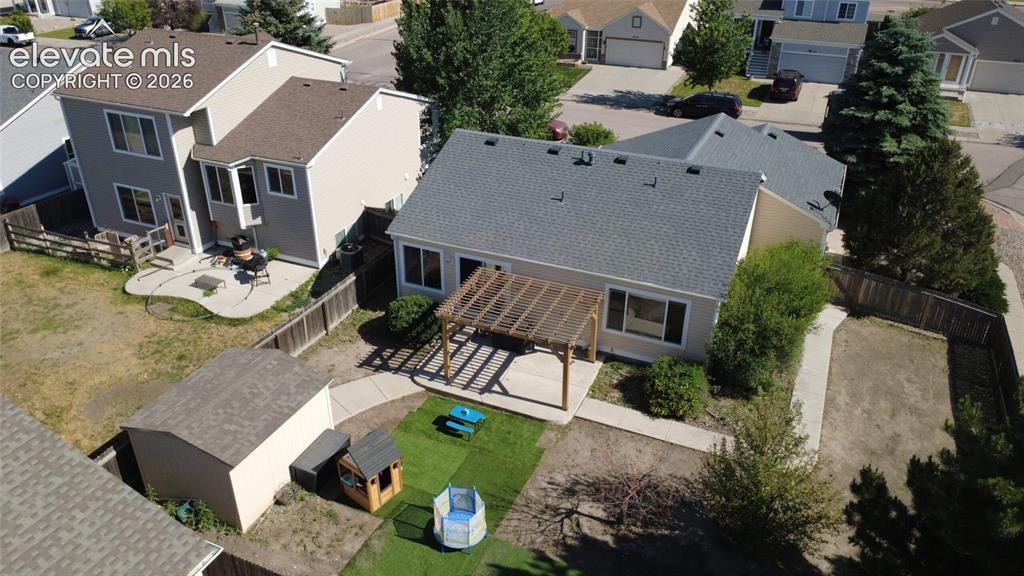 Image 29 of 31: Rear exterior of the home with a gray shingle roof and beige siding