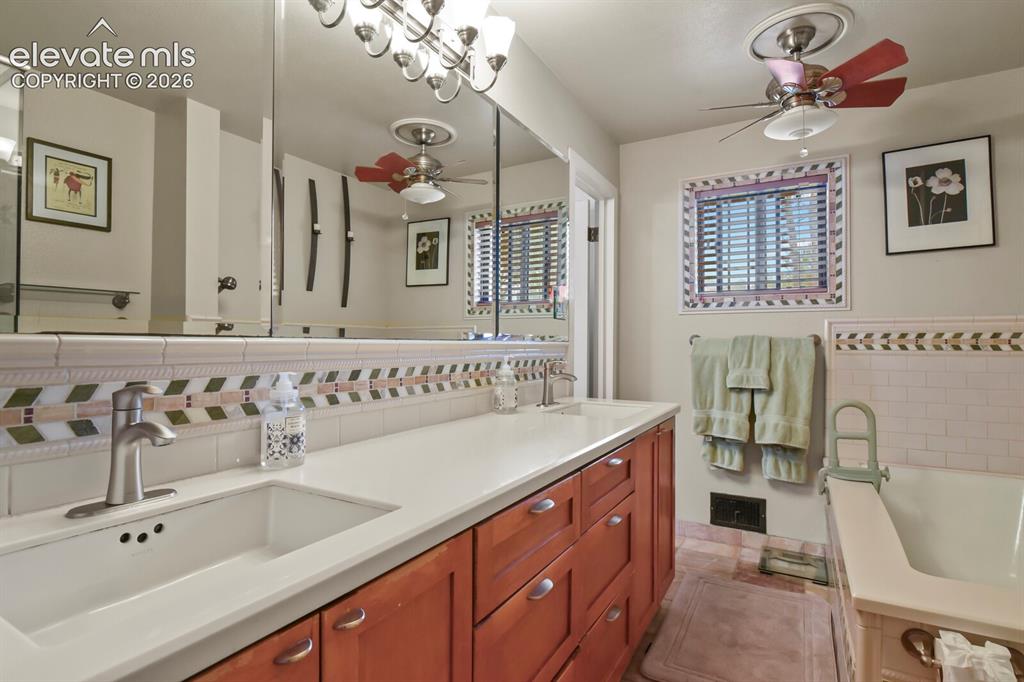 Image 12 of 28: Dual sinks with chrome fixtures, wood-finish cabinetry, and a white counter