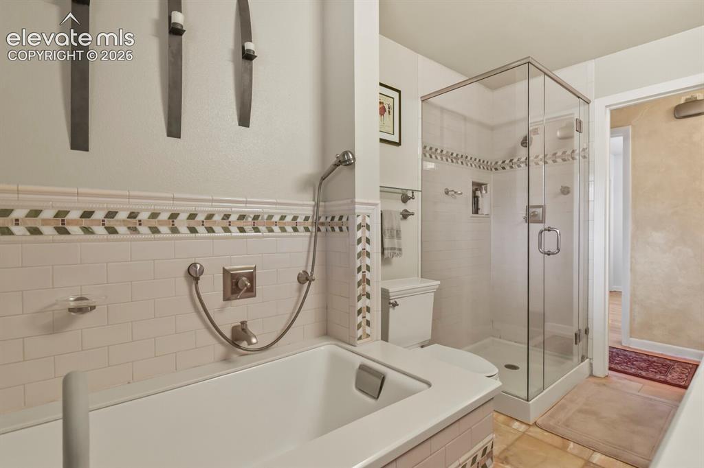 Image 13 of 28: White subway tile bath surround with decorative accent band
