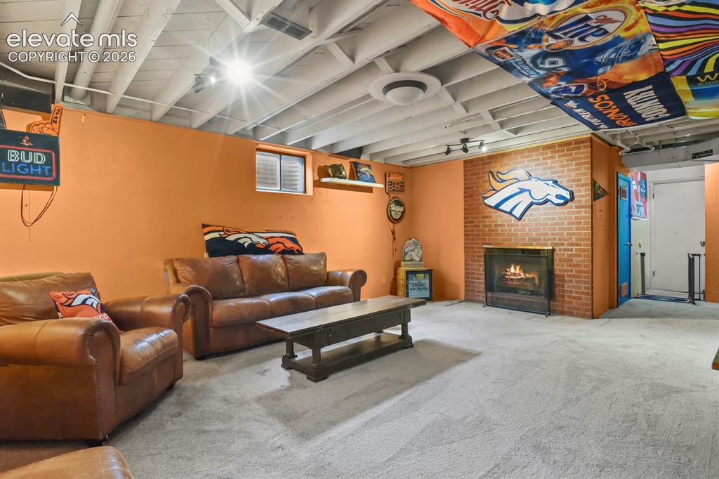 Image 18 of 28: Lower level room featuring brick-surround fireplace, exposed beam ceiling, 