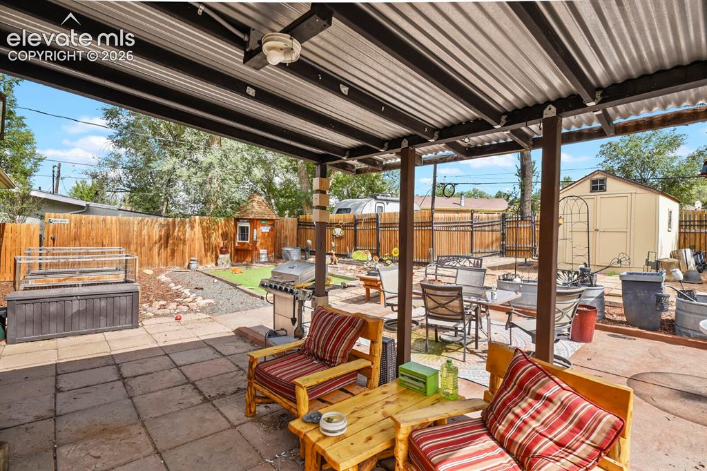 Image 21 of 28: Covered patio with corrugated metal roof and exposed wood beams