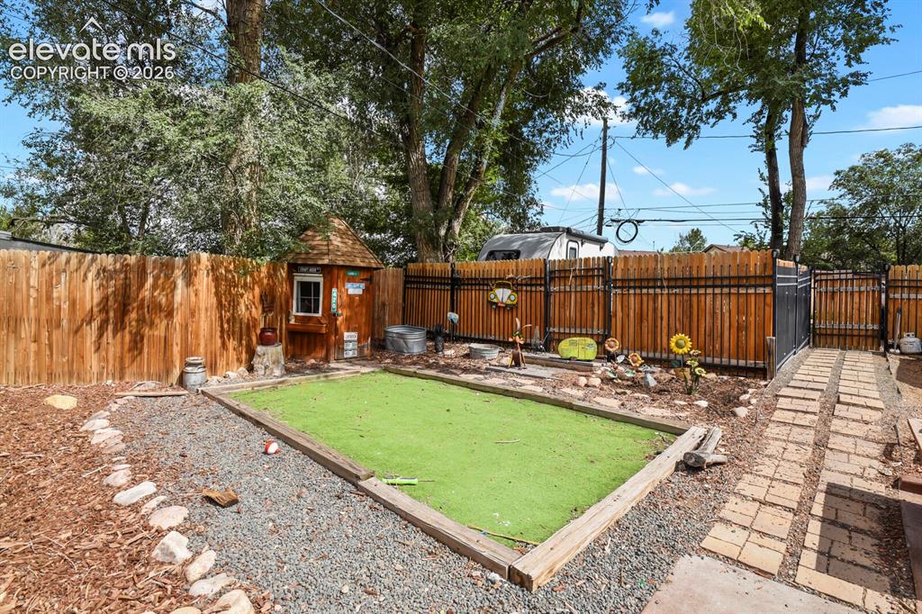 Image 23 of 28: Enclosed outdoor area featuring a manicured artificial turf patch, a wooden