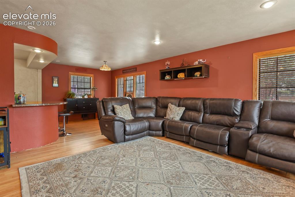 Image 3 of 28: Wood-finish flooring, recessed lighting, and a built-in snack bar with a st