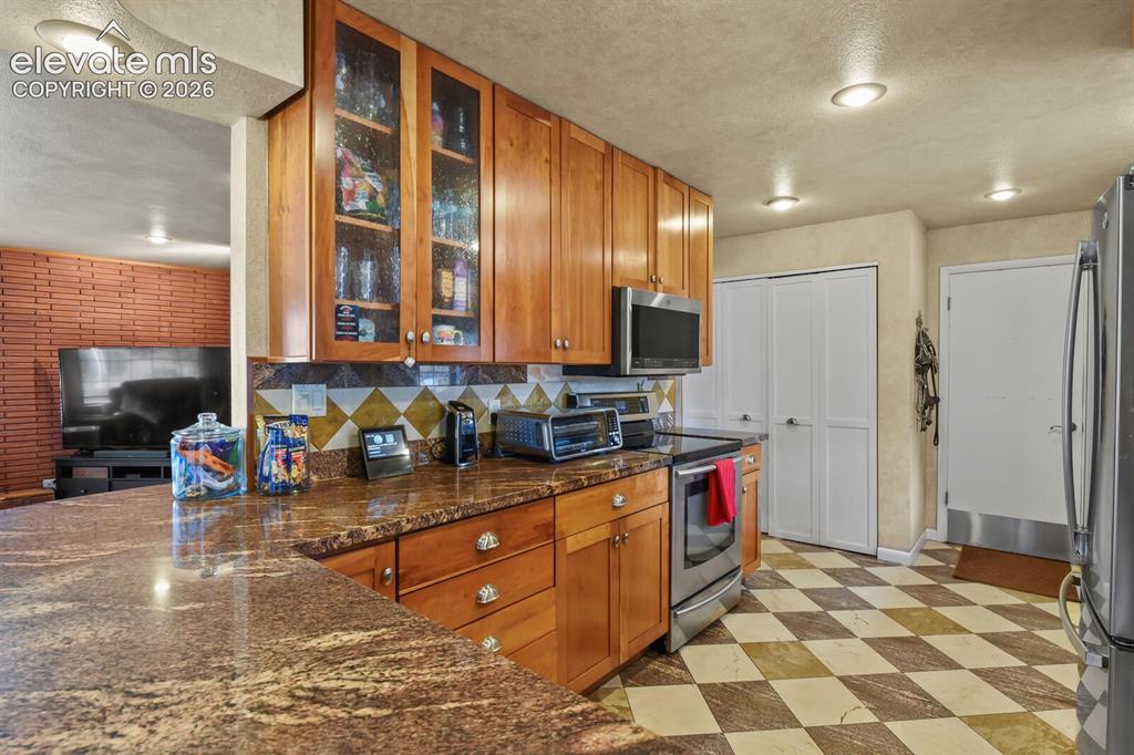 Image 7 of 28: Granite countertops, full-height wood cabinetry with glass-front uppers, st