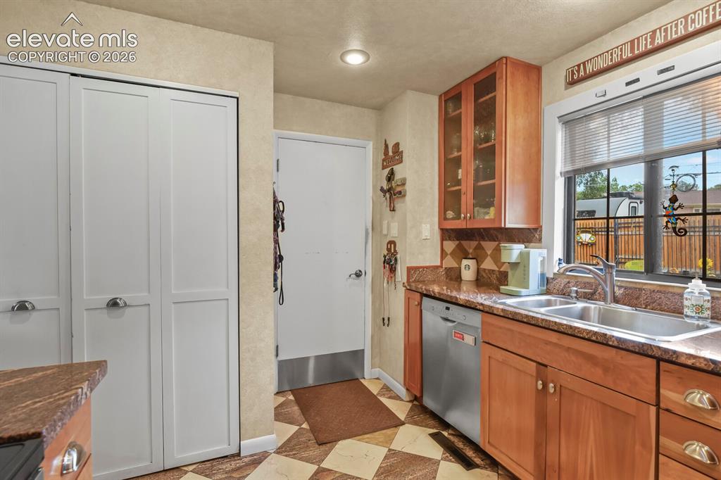 Image 9 of 28: Wood-finish cabinetry with glass-front uppers, stainless steel dishwasher, 