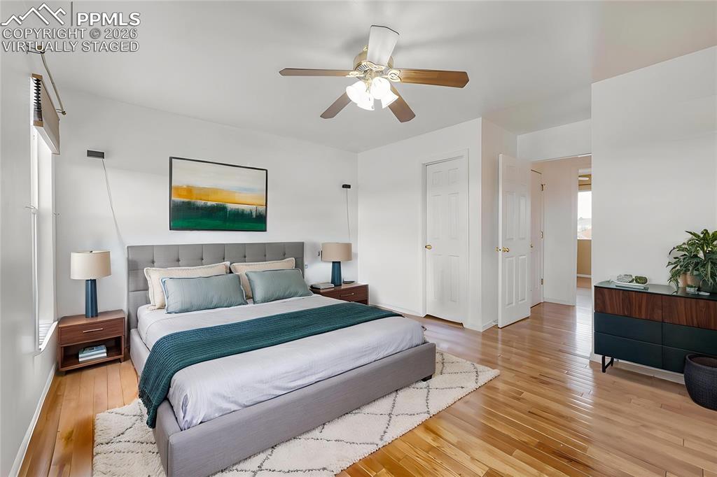 Image 14 of 30: Virtually staged primary bedroom Bright room featuring wood-finish flooring