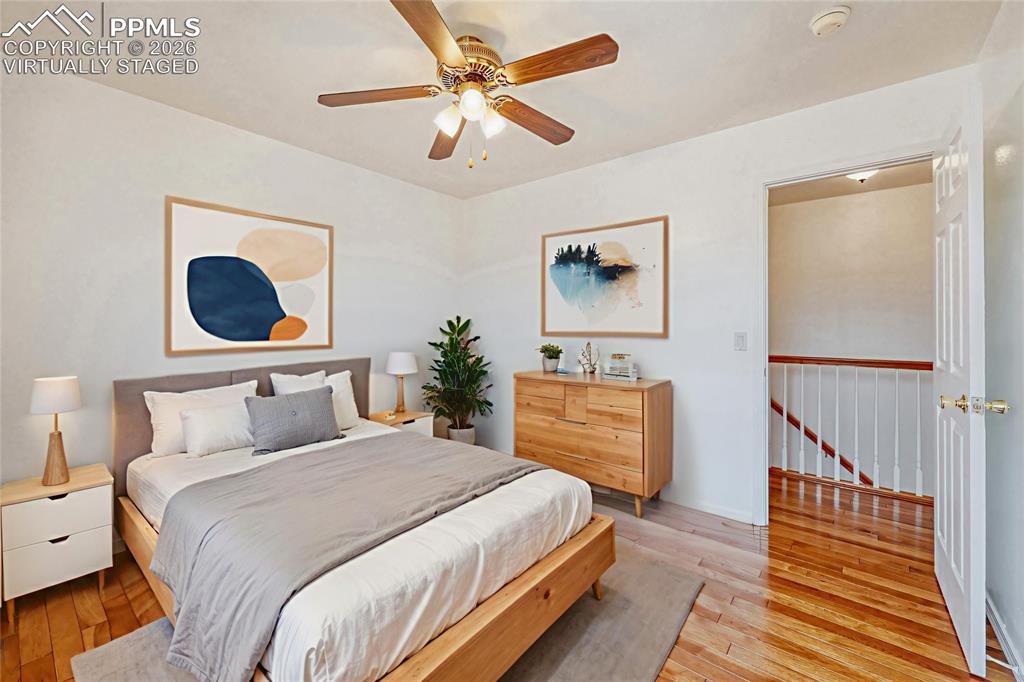 Image 18 of 30: Virtually Staged Bedroom Hardwood flooring throughout, ceiling fan with int