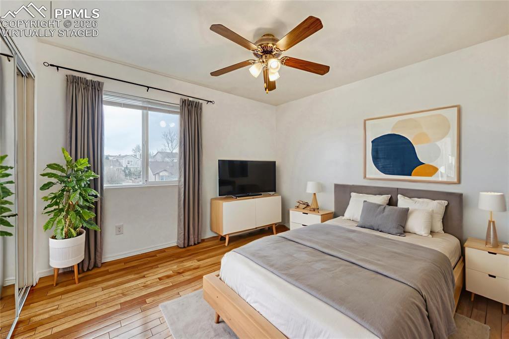 Image 20 of 30: Virtually Staged Spacious bedroom featuring wood-finish flooring, a contemp