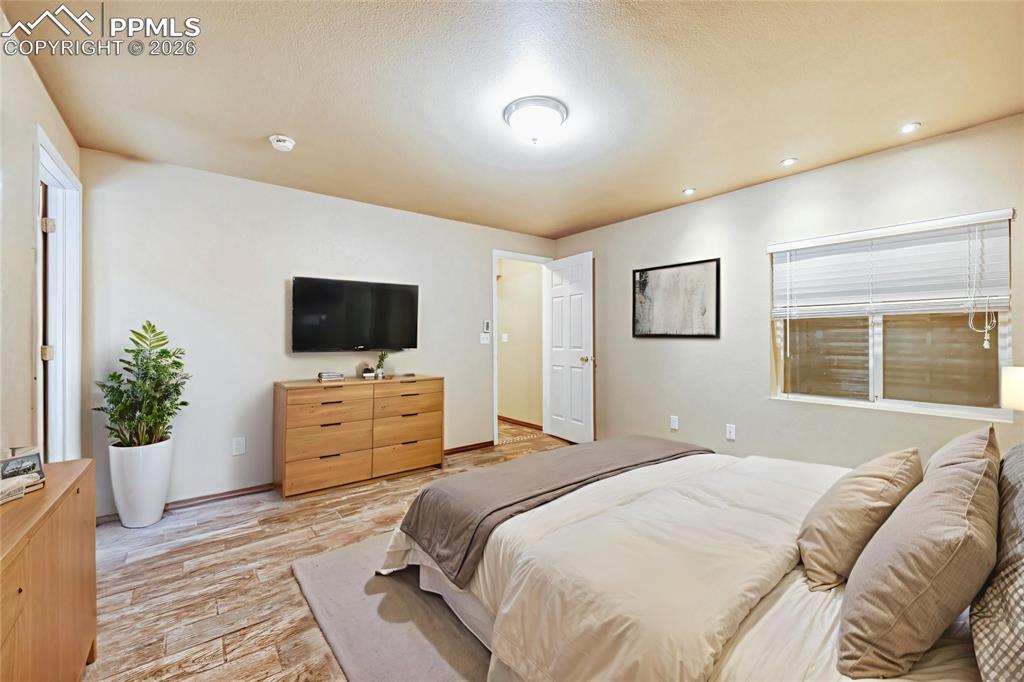 Image 27 of 38: Bedroom with light wood-style floors, recessed lighting, and a textured cei