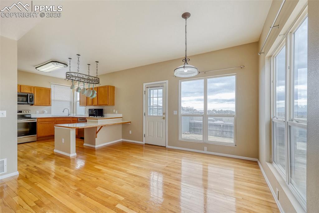 Image 9 of 30: Open-concept kitchen and dining area featuring light wood-finish flooring,