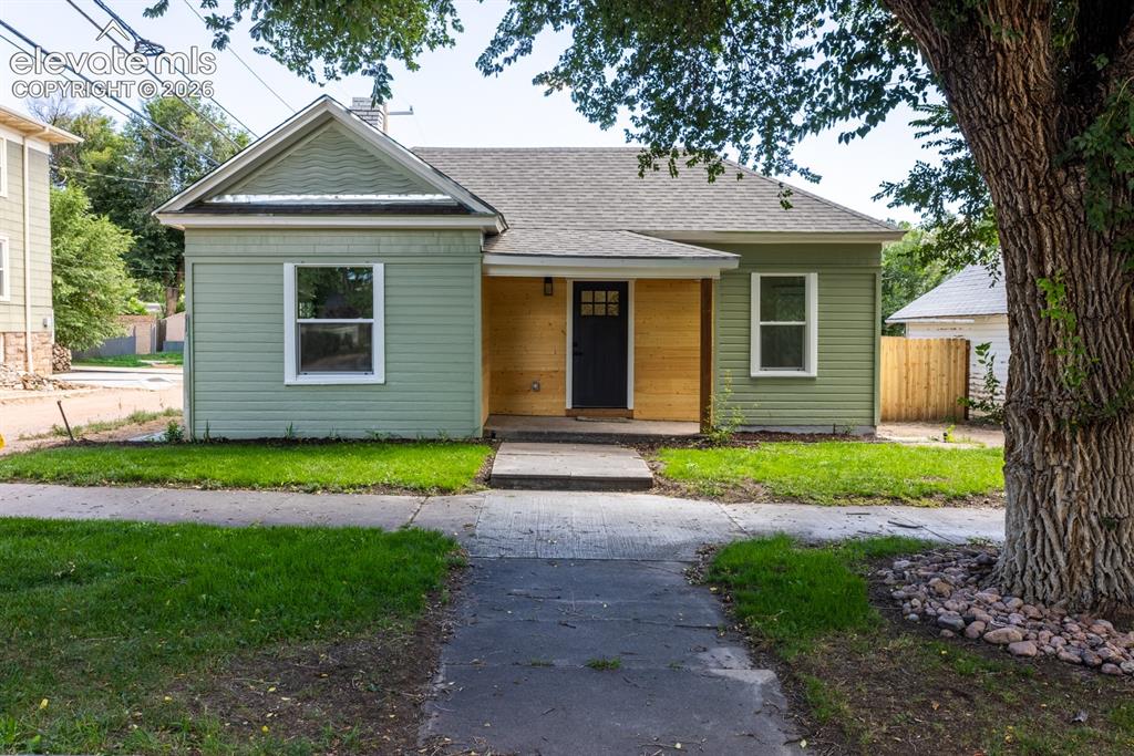 Image 14 of 19: Green siding exterior with a contrasting wood-finish accent wall