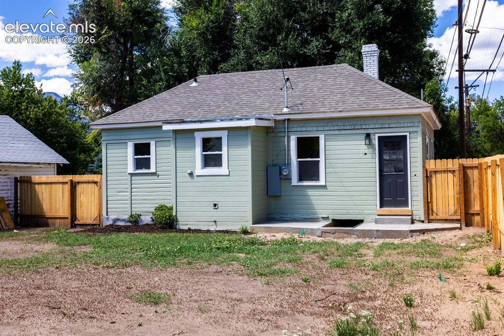 Image 15 of 19: Light green horizontal siding exterior with white window trim, a dark entry