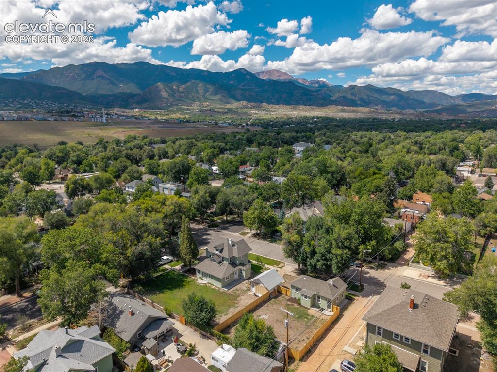Image 18 of 19: Residential properties situated among mature trees, with mountain scenery i