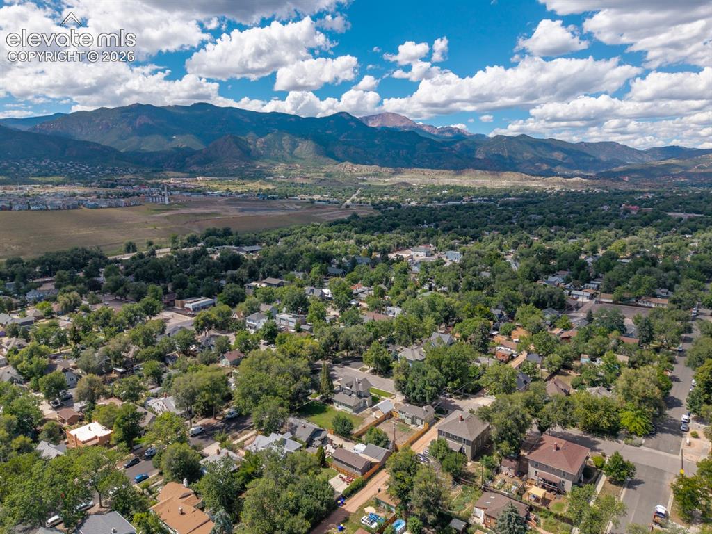 Image 19 of 19: Expansive mountainous backdrop frames a residential area with mature tree c