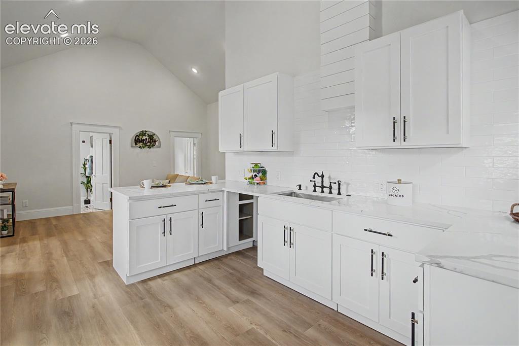 Image 7 of 19: White shaker cabinetry with dark hardware, stone countertops, subway tile b