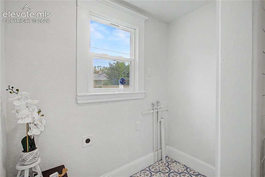 Image 8 of 19: Window with white trim and sill, white textured walls, and patterned floor 