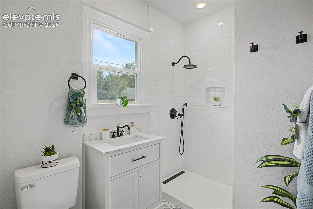 Image 9 of 19: White vanity with a stone countertop, black faucet, and undermount sink