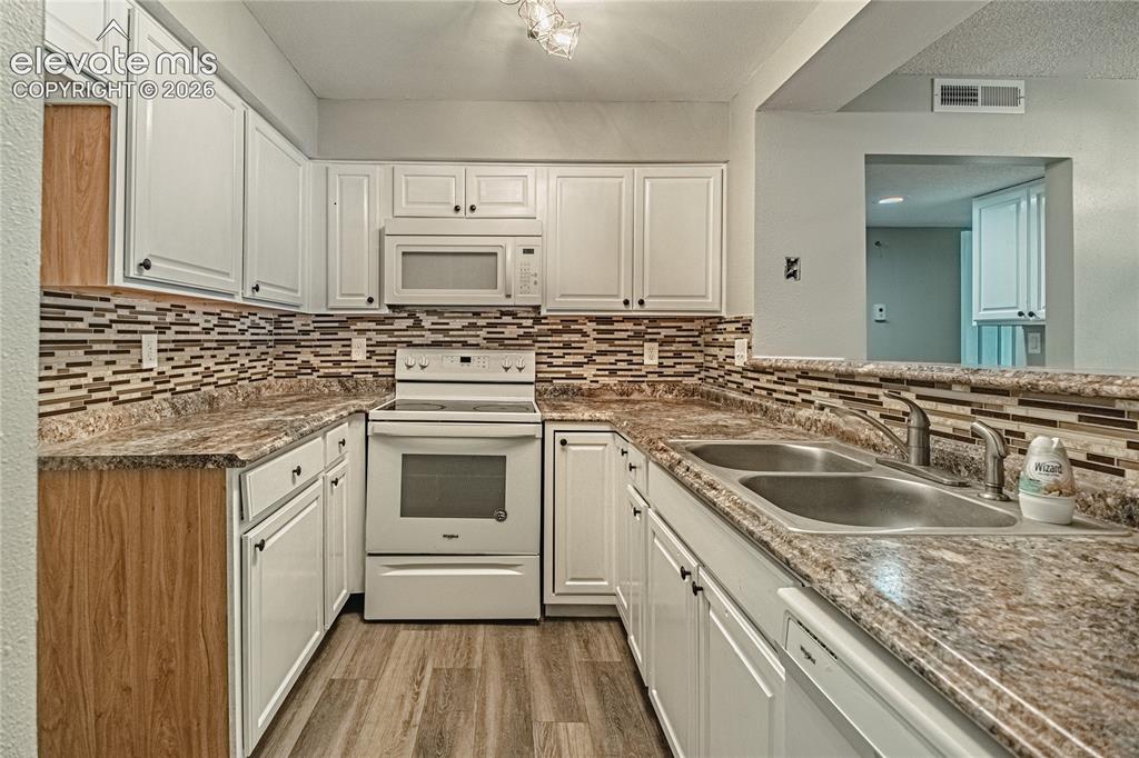 Image 12 of 37: Kitchen featuring white cabinetry, a white electric range, a built-in micro