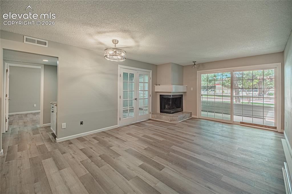 Image 14 of 37: Spacious living area featuring light wood-finish flooring, a corner firepla