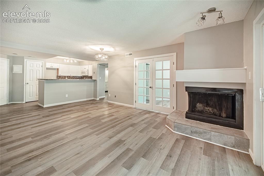 Image 15 of 37: Spacious living area featuring wood-finish flooring, a fireplace with a til