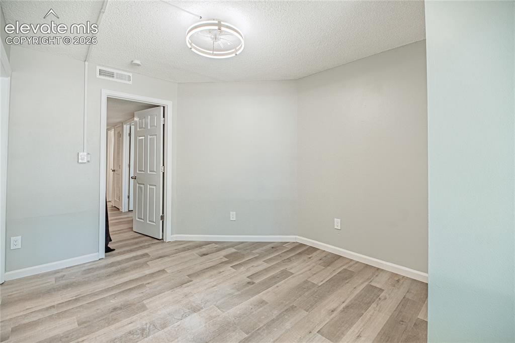 Image 19 of 37: Room featuring light gray walls, wood-finish flooring, a modern circular ce