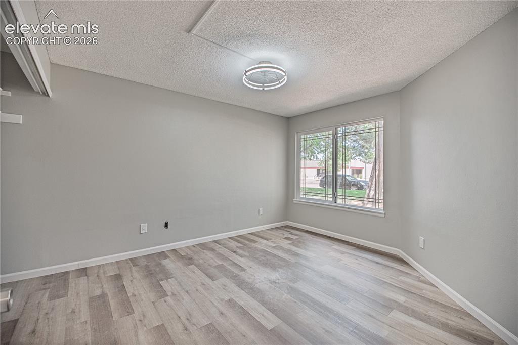 Image 21 of 37: Room featuring wood-finish flooring, light grey painted walls, and a textur
