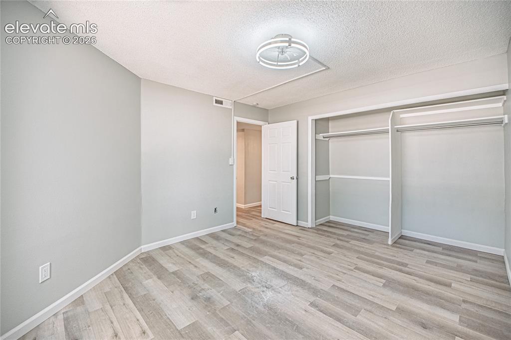 Image 22 of 37: Spacious room featuring light-toned walls, wood-finish flooring, a contempo
