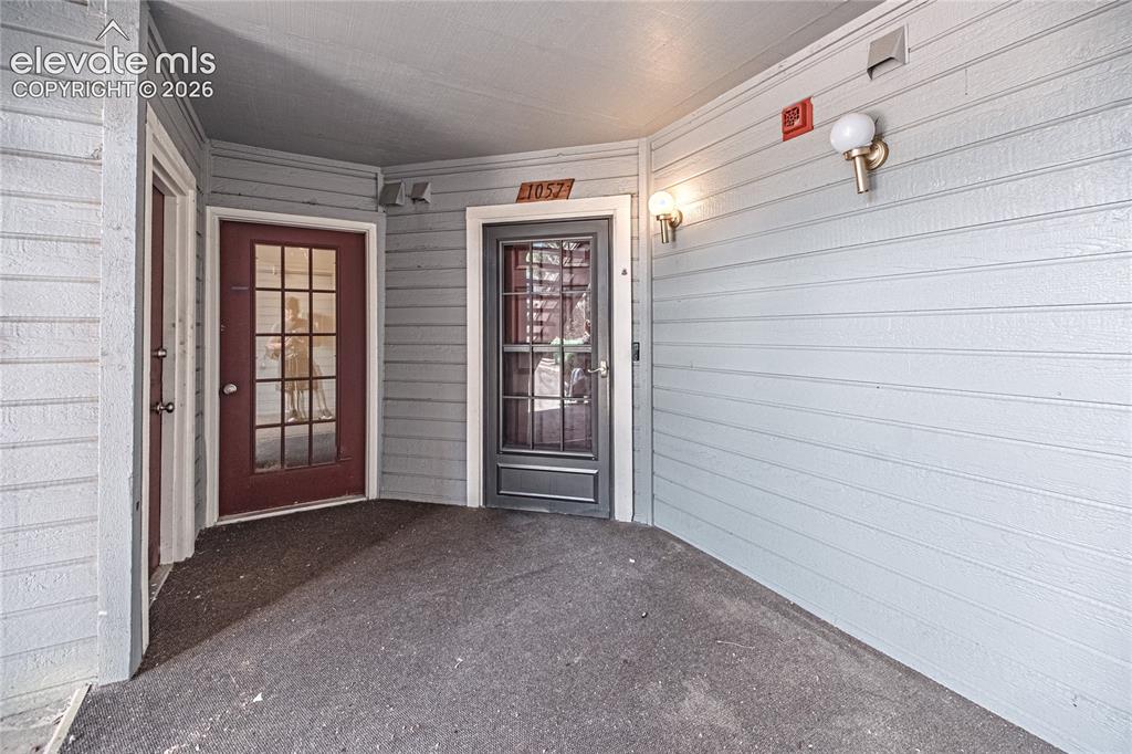 Image 4 of 37: Covered entryway featuring light gray siding, dark gray flooring, and two d