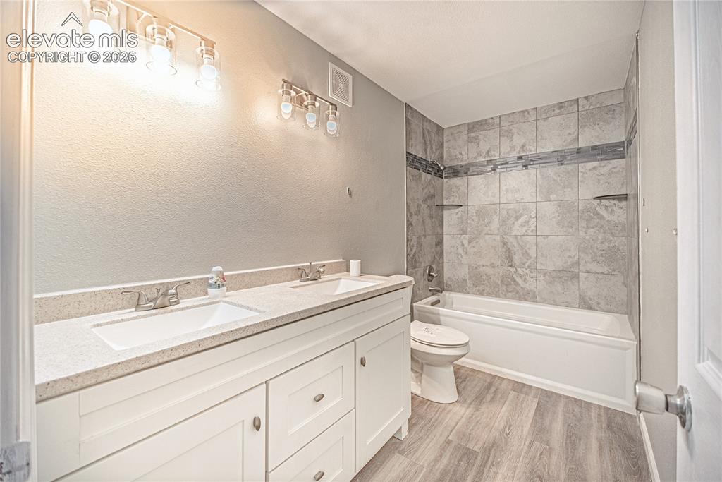 Image 8 of 37: Bathroom featuring a double vanity with white cabinetry and light-toned cou