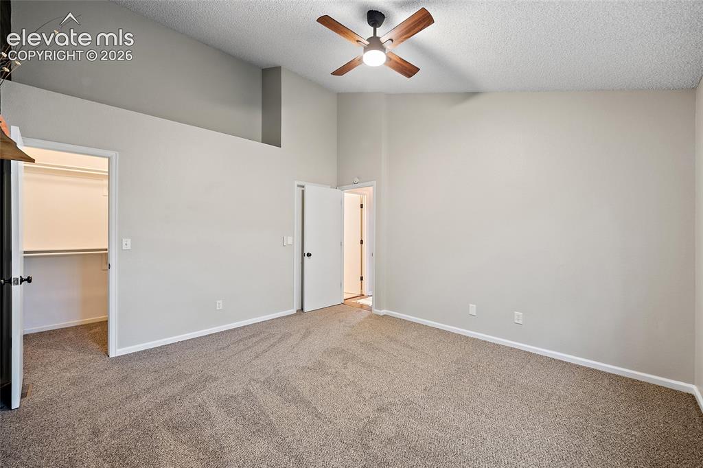 Image 11 of 37: Spacious room featuring vaulted ceilings, a ceiling fan with light, plush c