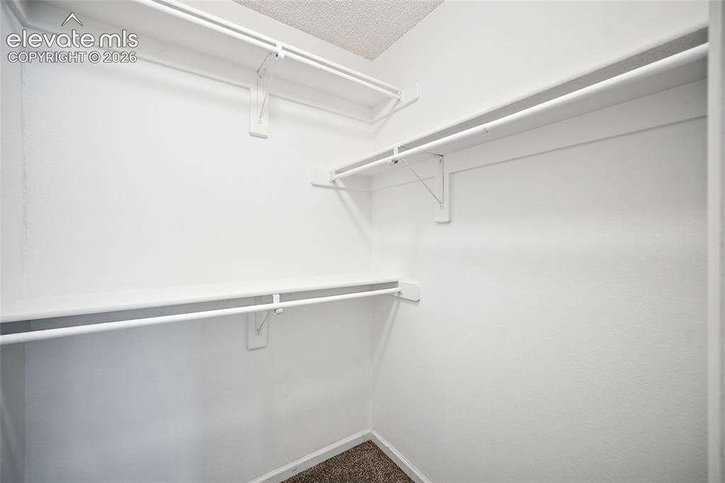 Image 12 of 37: Walk-in closet with white shelving and hanging rods
