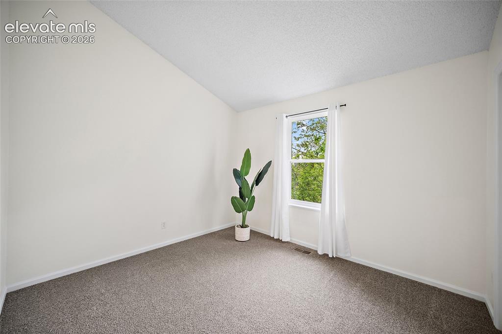 Image 13 of 37: Bright interior room featuring a window with white trim, neutral carpet flo