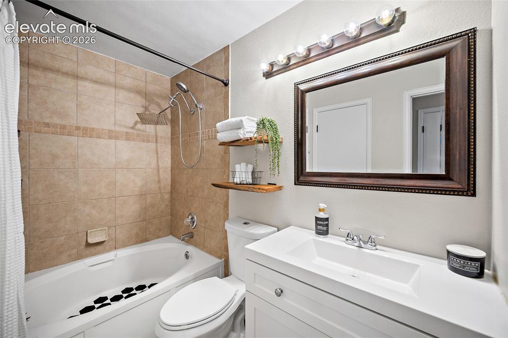 Image 16 of 37: Bathroom featuring a white vanity with integrated sink, large framed mirror