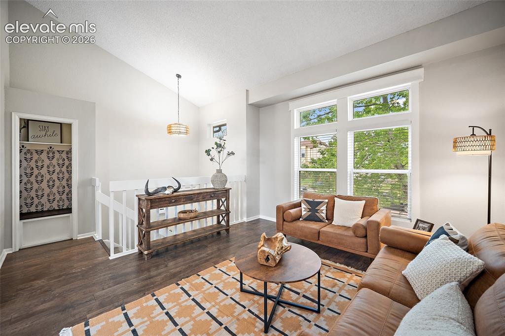 Image 17 of 37: Living area featuring vaulted ceilings, wood-finish flooring, and multiple 