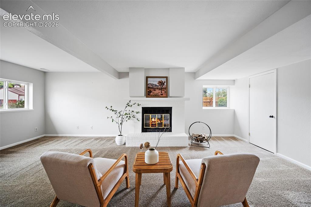 Image 19 of 37: Spacious room featuring a central white brick fireplace with a mantel, ligh