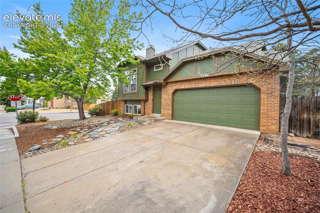 Image 2 of 37: Two-story residence featuring a brick facade with green siding, an attached