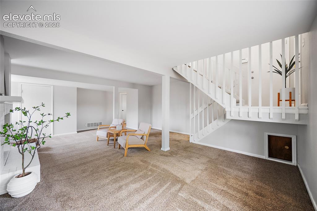 Image 21 of 37: Living area featuring a carpeted floor, white painted walls, and a white st