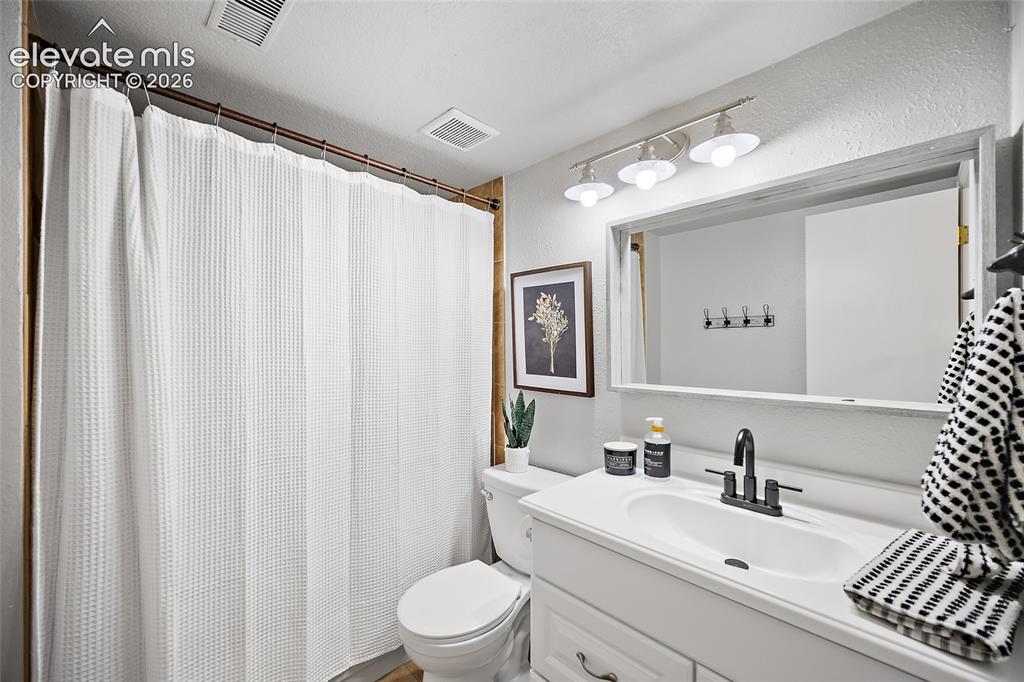 Image 23 of 37: Bathroom featuring a white vanity with integrated sink, black-finish faucet